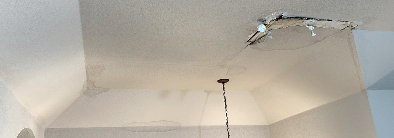 Visible water damage on a ceiling — staining, bubbling paint, and soft drywall